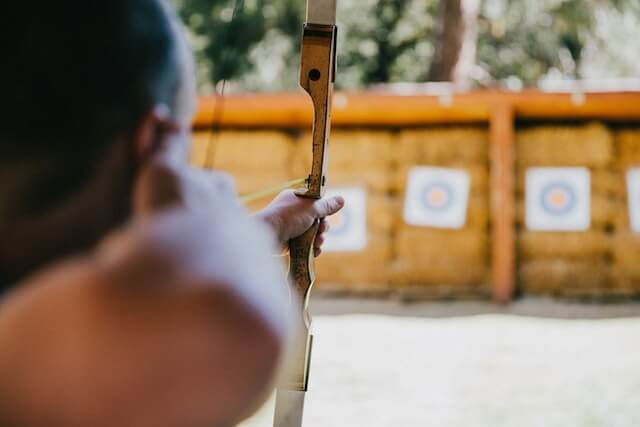 man aiming recurve bow